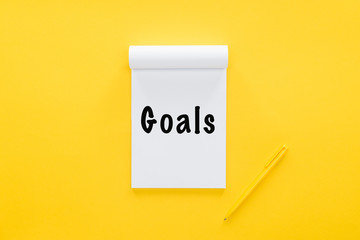 top view of notebook with 'goals' word on yellow, goal setting concept