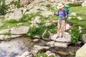 A hiker woman travels along small river during GR11 Hike in Pyrenees mountains