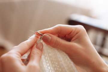 The woman hands knit natural woolen clothes. Knitting needles close-up. Horizontal photo. Freelance creative working. Handcraft concept