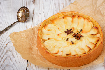 Traditional holiday apple pie. Baked dessert with anise, cloves and apples on light wooden...