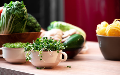 Microgreen in a white plate on a light wooden table close up. Concept of melting food and plant food. Greens close up
