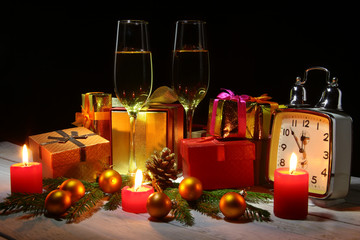 Happy holiday decoration with Christmas balls, gift boxes, watch and candles. New Year's tree, cone and glass with champagne.