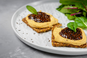 Obraz na płótnie Canvas Vegan caviar made with chia seeds and nori. Appetizers on whole grain crispbreads with hummus