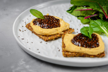 Vegan caviar made with chia seeds and nori. Appetizers on whole grain crispbreads  with hummus