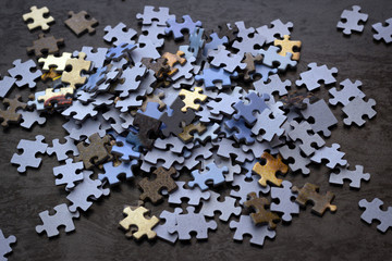 Puzzle pieces on a wooden surface, closeup, top view. A puzzle is a puzzle from small pieces. Texture of puzzles. Copy space
