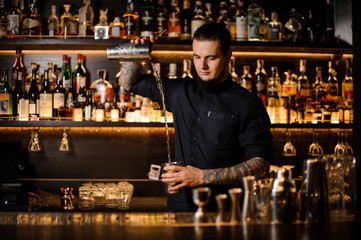 Bartender pouring the cocktail from the steel shaker