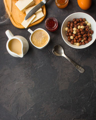 cornflakes, coffee, cottage cheese, bread, butter, eggs, jam and other ingredients for breakfast on a dark background. Top view with copy space