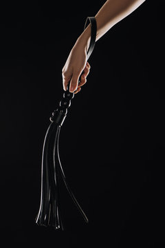 cropped view of female hand holding leather flogging whip isolated on black  Stock Photo