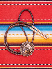Vintage Sterling Silver Bolo Tie with Concho and Silver Tips on colorful southwestern hand woven fabric.