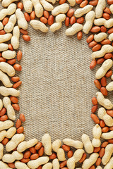 Roasted peanuts in a shell and peeled on a brown fabric background.