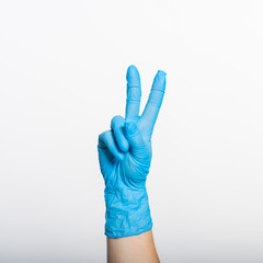 Hand in a blue glove with a sign-Victory, on a white background.