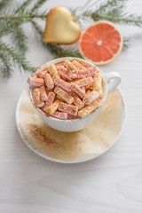 Christmas still life, attributes of the new year, a cup of coffee, a souffle, a golden Christmas decoration in the shape of a heart, a fir branch and a slice of grapefruit on a wooden background