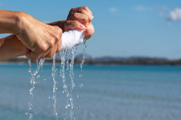 Hands squeeze wet white cloth.