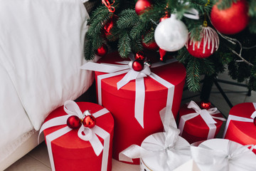 Lots of beautifully wrapped Christmas presents in red and white under the Christmas tree. Round boxes. Concept of Christmas and New Year holidays. 