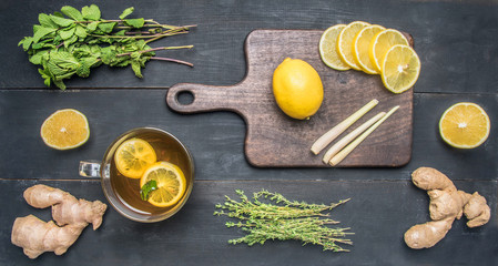 flavored tea with lemon, and herbs, lined with ingredients, mint, thyme, cinnamon and ginger on a wooden rustic background