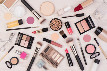 Makeup cosmetics such as eyeshadows, lipstick, mascara and makeup accessories on white, wooden...