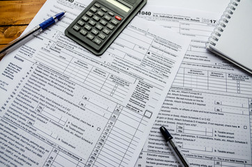 1040 tax form, pens, calculator and notepad on the table