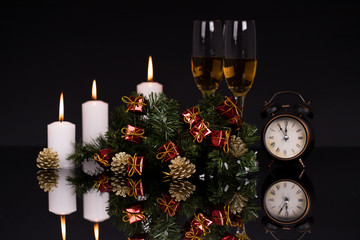 Glasses with champagne,candles, clock and Christmas ornaments