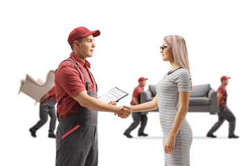 Mover shaking hands with a woman and movers carrying furniture in the back