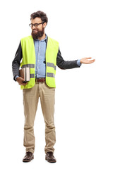 man holding books, wearing safety vest, gesturing welcome with hand and looking to the side