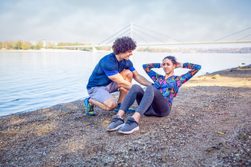 fitness, sport, training, gym and lifestyle concept -Trainer assisting young woman doing sit-ups.