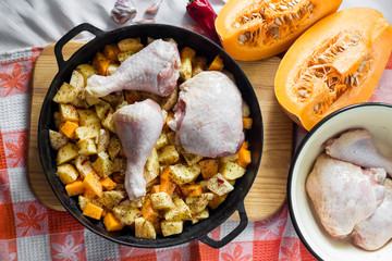 Cooking one-pot meal - chicken thighs and legs with potatoes and pumpkin