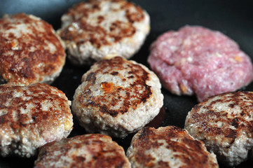 Cutlets in a pan occupy the entire space of the frame. One of the raw patties. Close-up. Macro shooting.