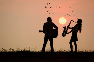musician play guitar and saxophone with sunset or sunrise background