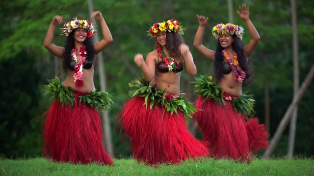 Barefoot Tahitian females in hula skirts and flower headdress performing a traditional dance at celebration ceremony French Polynesia South, Pacific,
