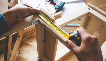 Man assembly wooden furniture,fixing or repairing house with tape measures
