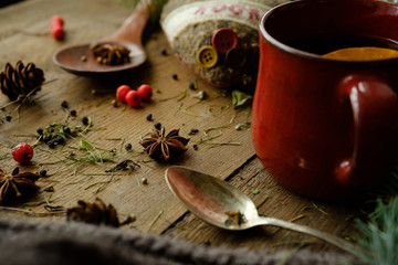 Details of still life in the living room home interior. Beautiful cup of tea with spices and sweaters on a wooden background. Cozy autumn-winter concept...
