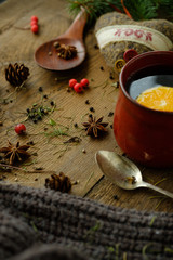 Details of still life in the living room home interior. Beautiful cup of tea with spices and sweaters on a wooden background. Cozy autumn-winter concept...