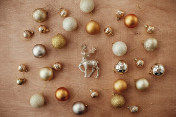 Merry Christmas. Christmas golden glitter reindeer and shiny baubles and balls on rustic background, flat lay. Modern gold decorations and present. Seasons greetings.  Happy holidays