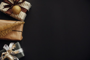 Christmas border of gift boxes ,tree ,reindeer and glitter baubles on stylish black background. Christmas flat lay with space for text. Seasons greetings, card mockup. Merry Christmas