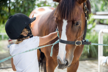 Young girl taking care of her horse at the farm