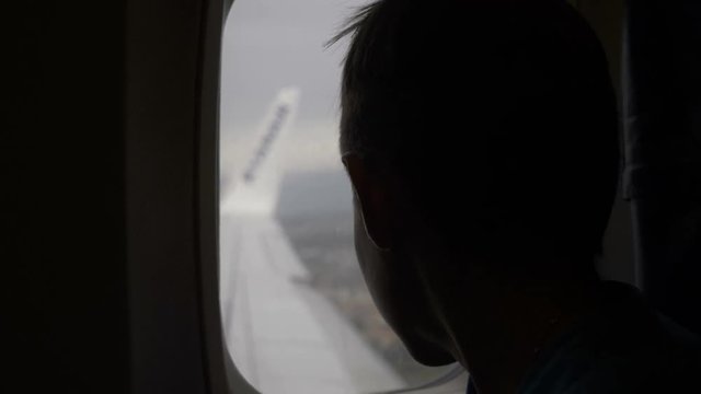 boy flies in an airplane and looks out the window