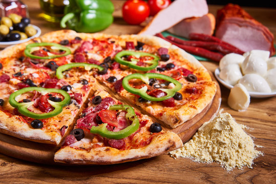 Hot big pepperoni pizza tasty pizza composition with melting cheese bacon tomatoes ham paprika on wooden background