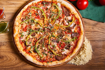 Hot big pepperoni pizza tasty pizza composition with melting cheese bacon tomatoes ham paprika on wooden background