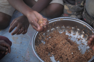 kids eating brown rice and fish in Africa - closeup