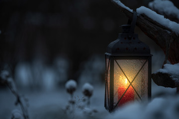Candle lantern in the snowy garden at dusk. © ekim