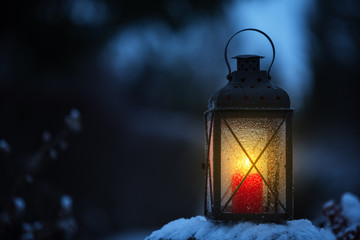 Candle lantern in the snowy garden at dusk. © ekim