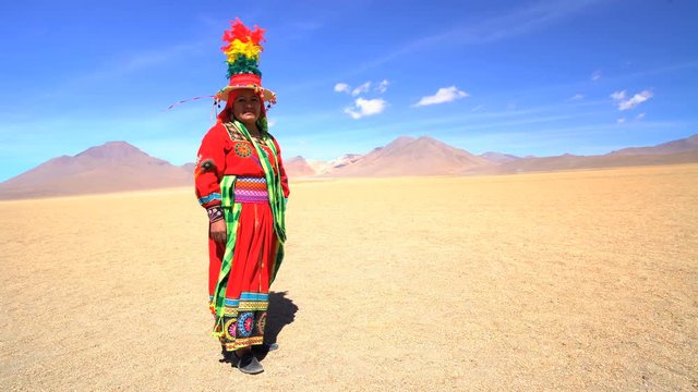 Latin American Indigenous women in Salvador Dali desert displaying traditional National Headdress and costume Bolivia South America
