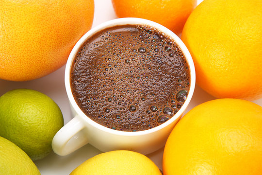 Black coffee in a white Cup surrounded by citrus fruits