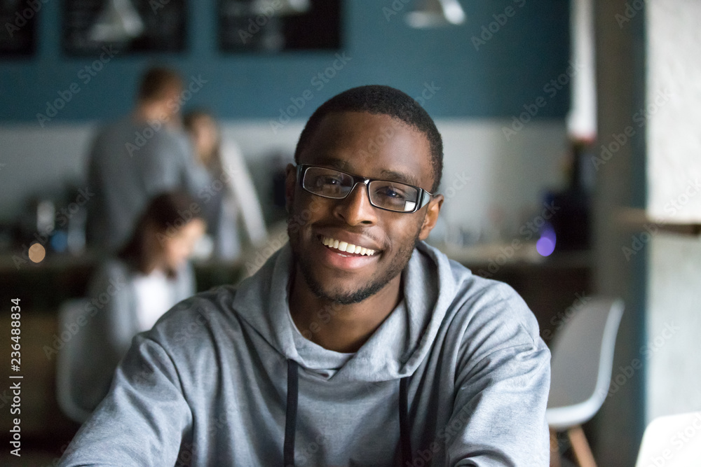 Wall mural portrait of smiling african american student looking at camera sitting in cafe, black millennial man - Wall murals
