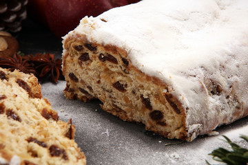 Traditional European Christmas pastry, fragrant home baked stollen, with spices and dried fruit. Sliced on rustic table with xmas tree branches and decorations