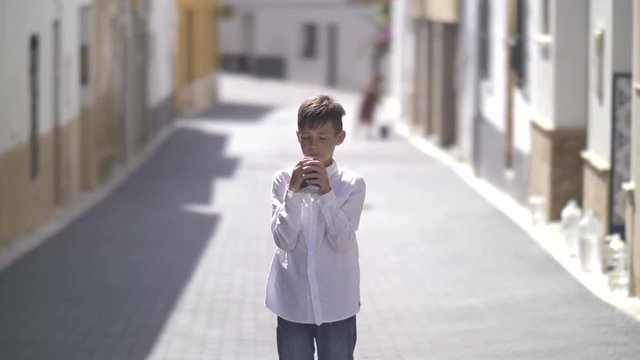 spanish boy drinking a drink outdoors standing near camera