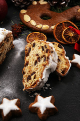 Traditional European Christmas pastry, fragrant home baked stollen, with spices and dried fruit. Sliced on rustic table with xmas tree branches and decorations