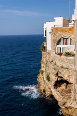 Fototapeta na wymiar Traditional houses on dramatic cliffs with caves rising from Adriatic sea in Polignano a Mare, Italy, sunny summer day