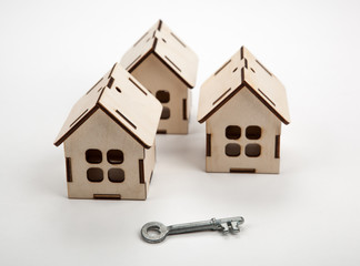 three wooden miniature houses and a door key on a white background