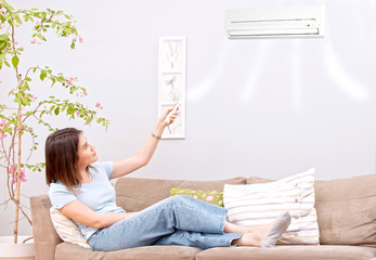 woman using remote control to air conditioner